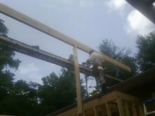 Carpenter setting a ridge beam over a new addition frame — Ice Dam Removal by Roofing Brothers in Crescent
