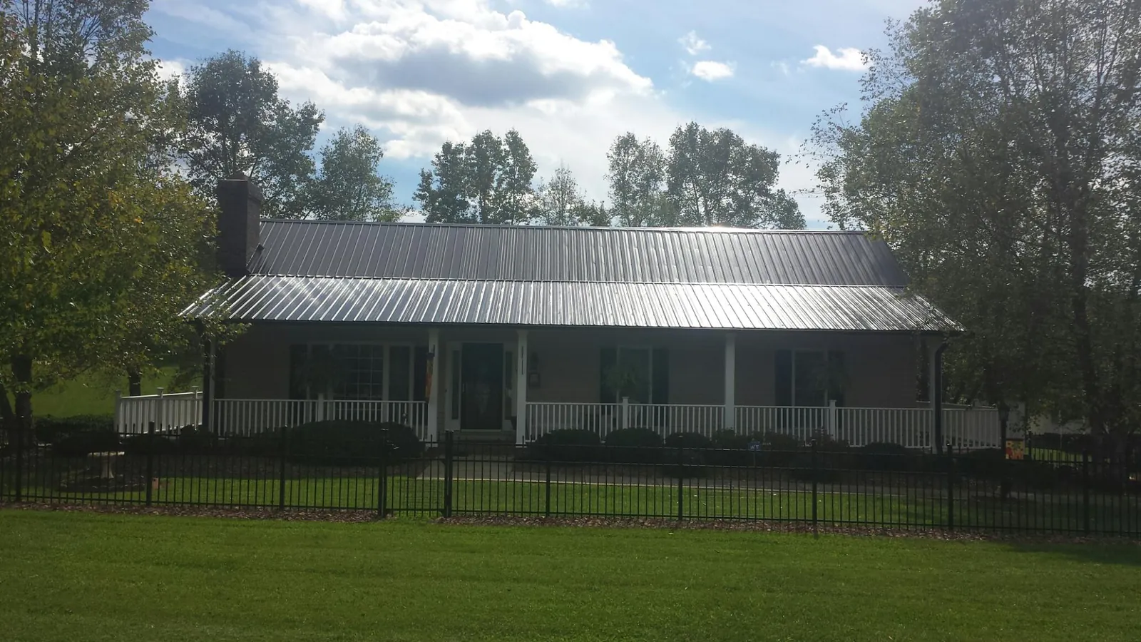 Gray metal roof on a brick ranch with a full width front porch — Gutter Guard Installation work by our crew in Crescent