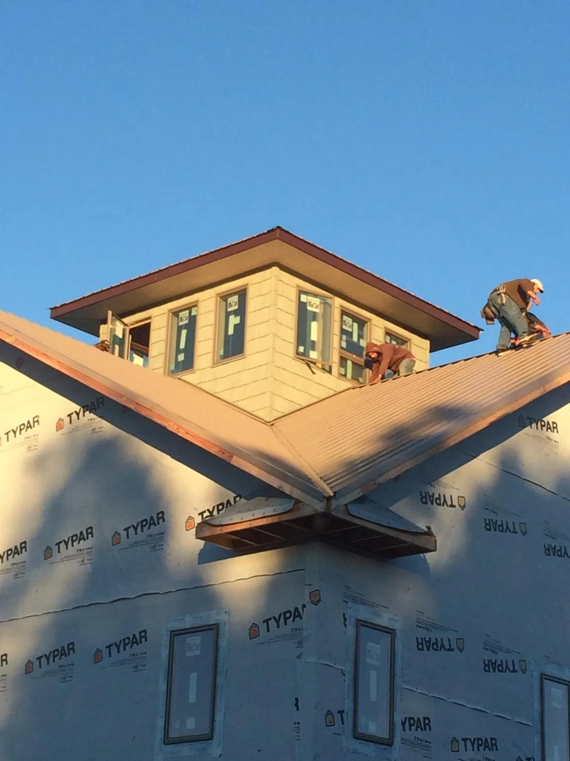 Roofers working around a rooftop cupola on a new metal roof at sunset — Roof Waterproofing in Crescent by Roofing Brothers